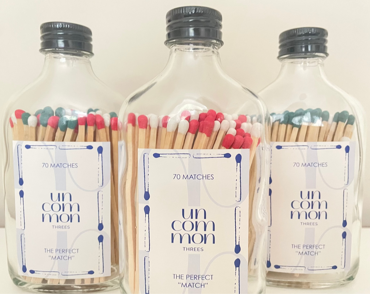 Black lid glass bottles filled with 9.8 cm red, dark green and white matches on a white background.