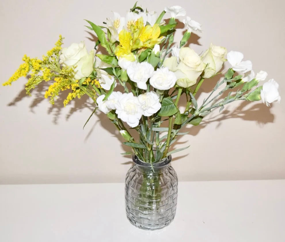 Blue ribbed glass vase with fresh flowers on a white surface.