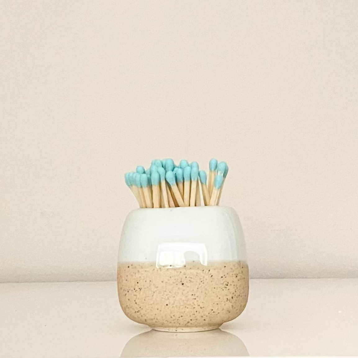 Blue ceramic match holder on a white surface.