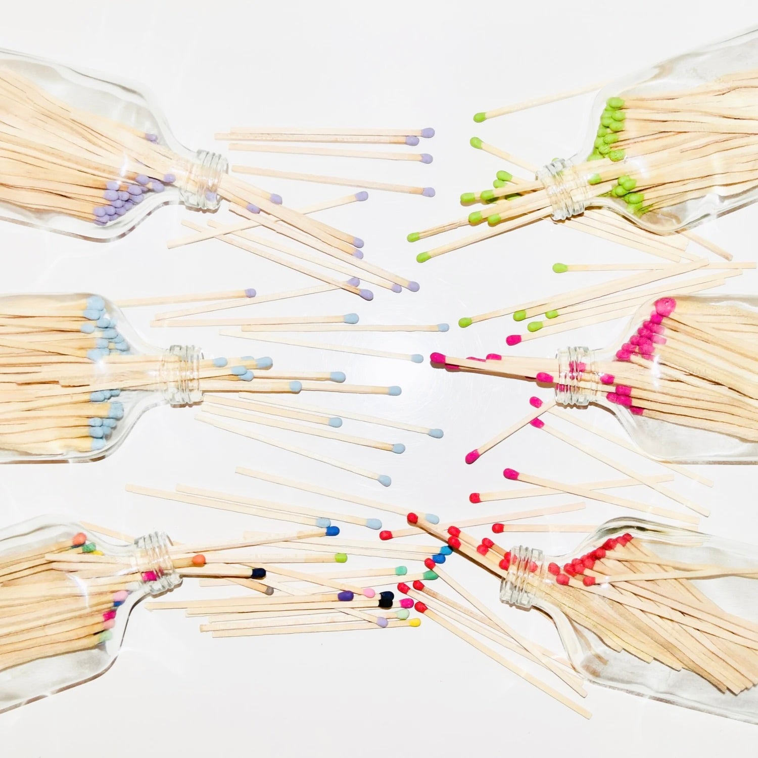 Glass matches bottles with matches spilling out on a white background.