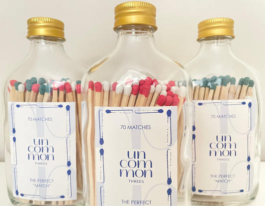 Gold lid glass bottles filled with 9.8 cm red, dark green and white long safety matches on a white background.