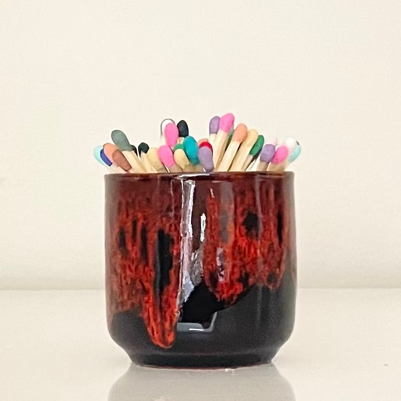 Orange glazed match holder filled with 7.5 cm refill matches (sold seperately) on white surface.