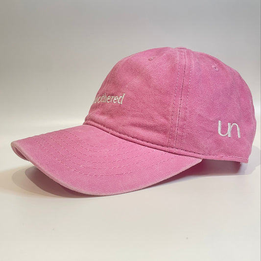 100% Pink washed cotton cap with 'unbothered' white embroidery with side emblem 'un'.