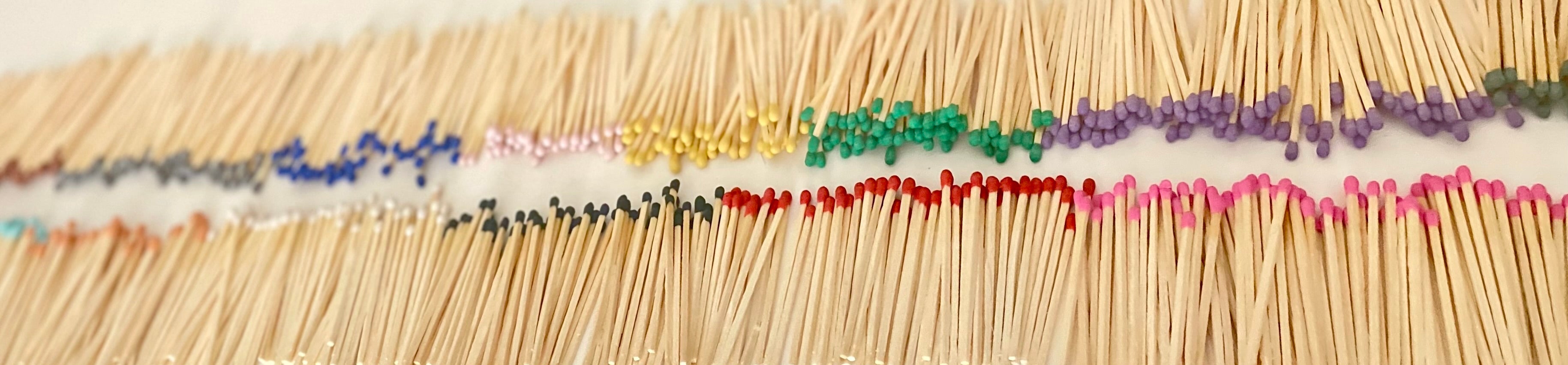 7.5 cm coloured tipped matches arranged in a row on a white surface.