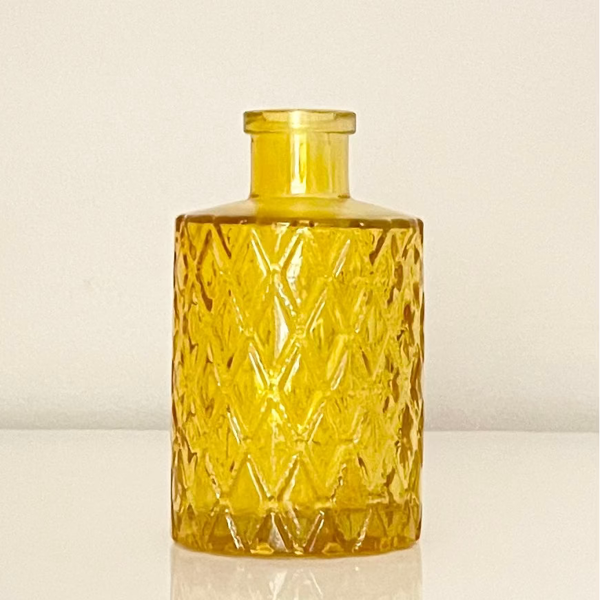 Mustard glass vase (A) with textured surface on a white background.