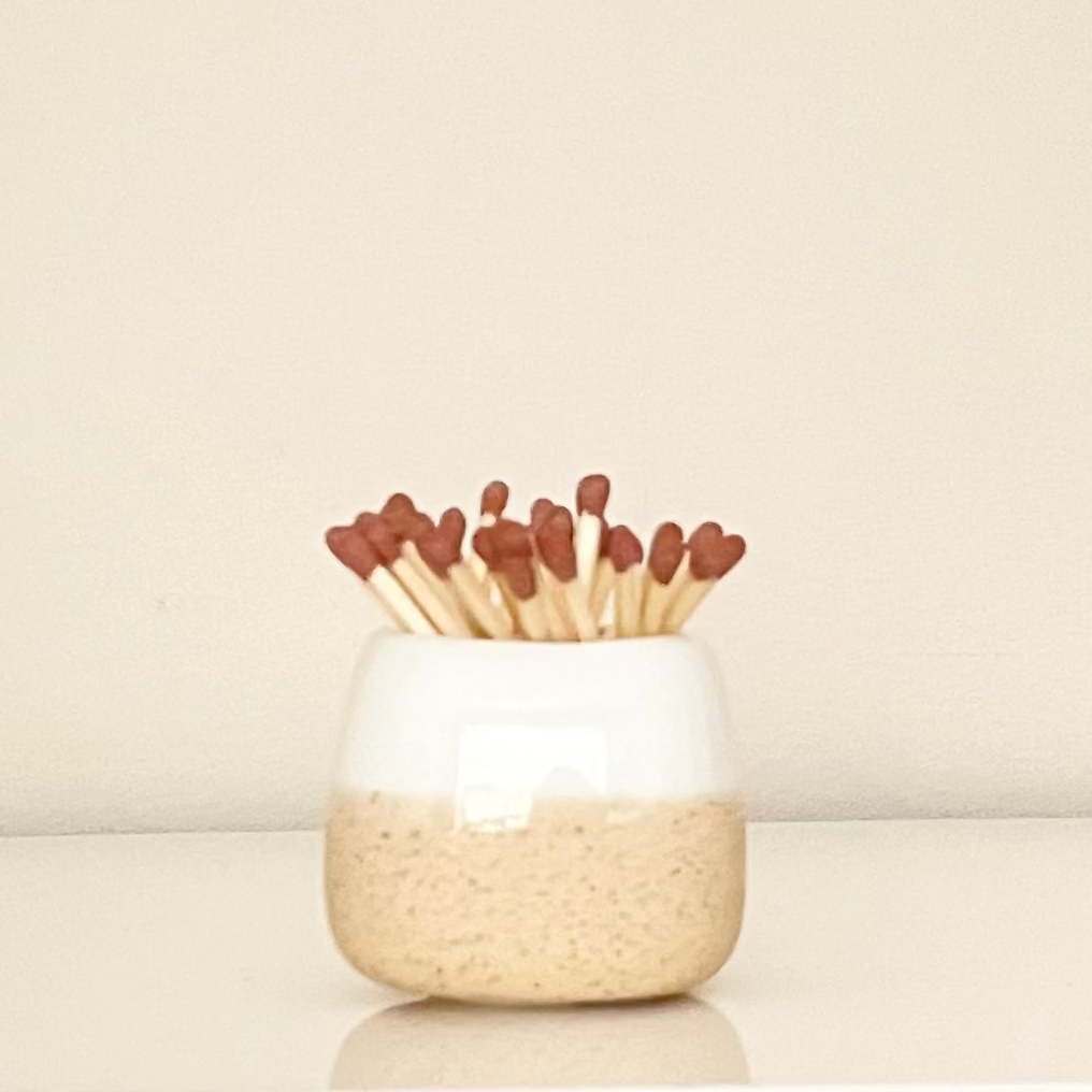 White ceramic match holder on a white surface.