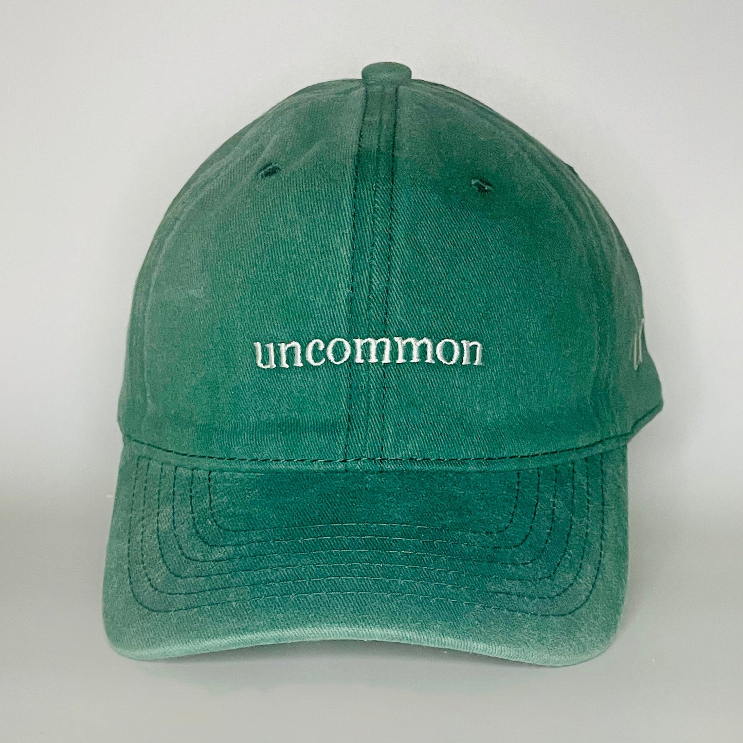 100% Green washed cotton cap with 'uncommon' white embroidery. 