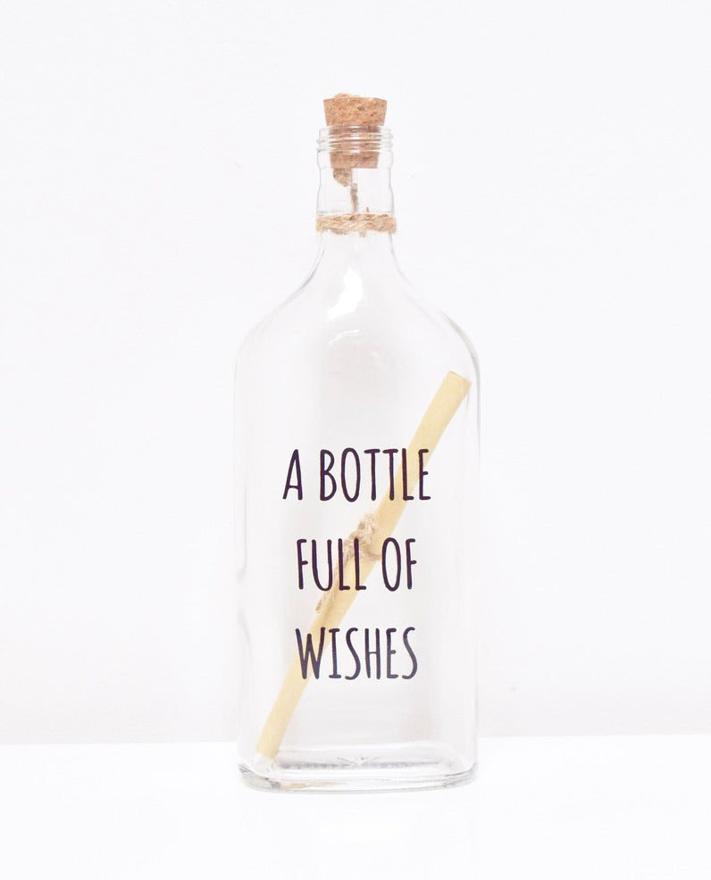 A glass bottle with a message "A BOTTLE FULL OF WISHES" and a cork lid, containing a scroll to write your personalised text.