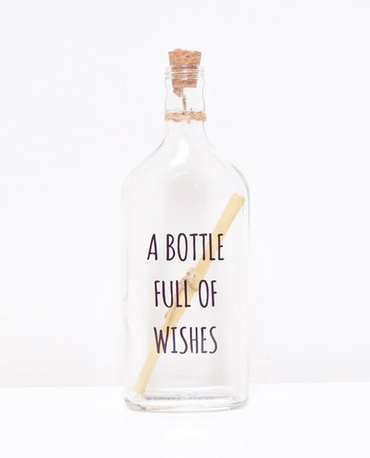 A glass bottle with a message "A BOTTLE FULL OF WISHES" and a cork lid, containing a scroll to write your personalised text.