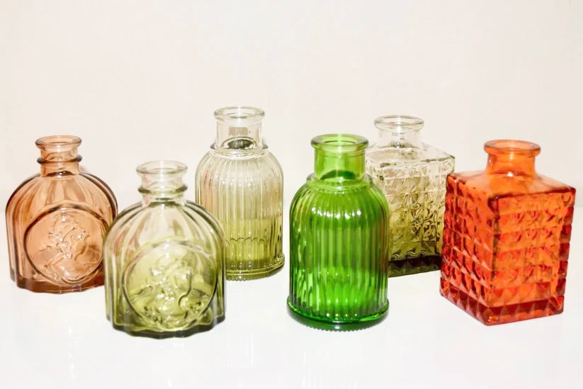 Artisanal colourful glass bottles on a white background.