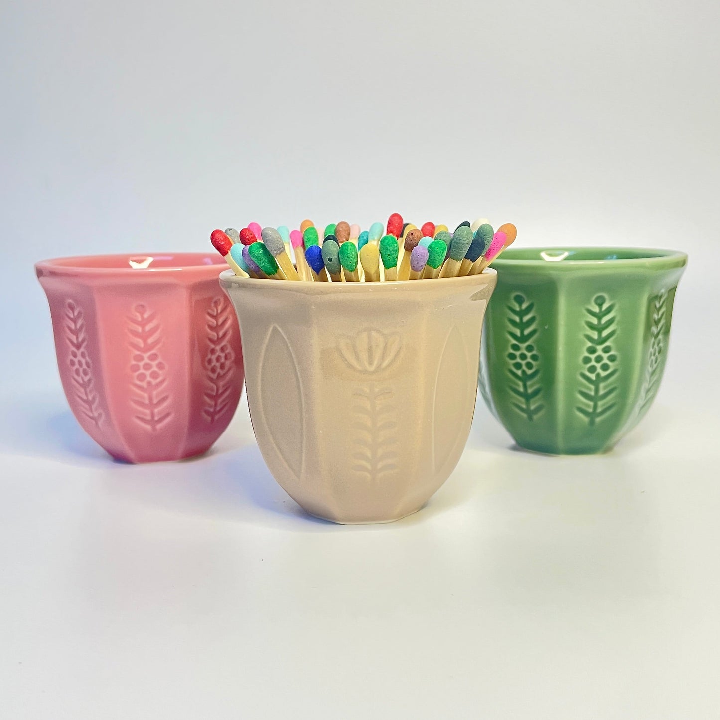 pink, beige and green match holder/coffee cup with flower design filled with coloured safety matches.