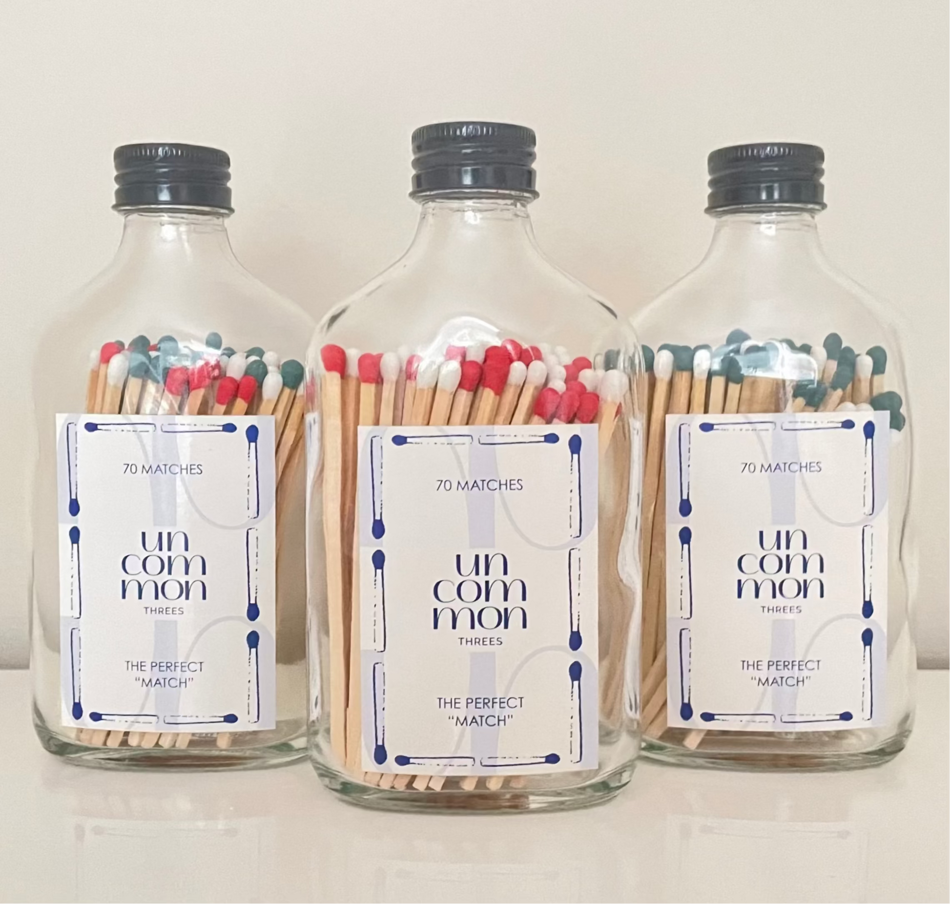 Black lid glass bottles filled with 9.8 cm red, dark green and white matches on a white background.
