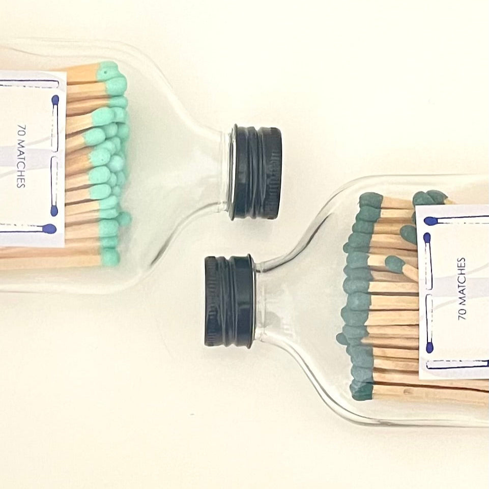 Two glass bottles filled with 9.8 cm coral and dark green long safety matches on a white background.