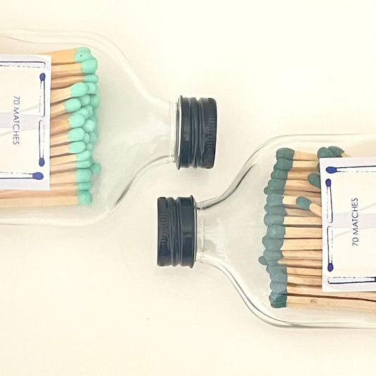Two glass bottles filled with 9.8 cm coral and dark green safety matches on a white background.