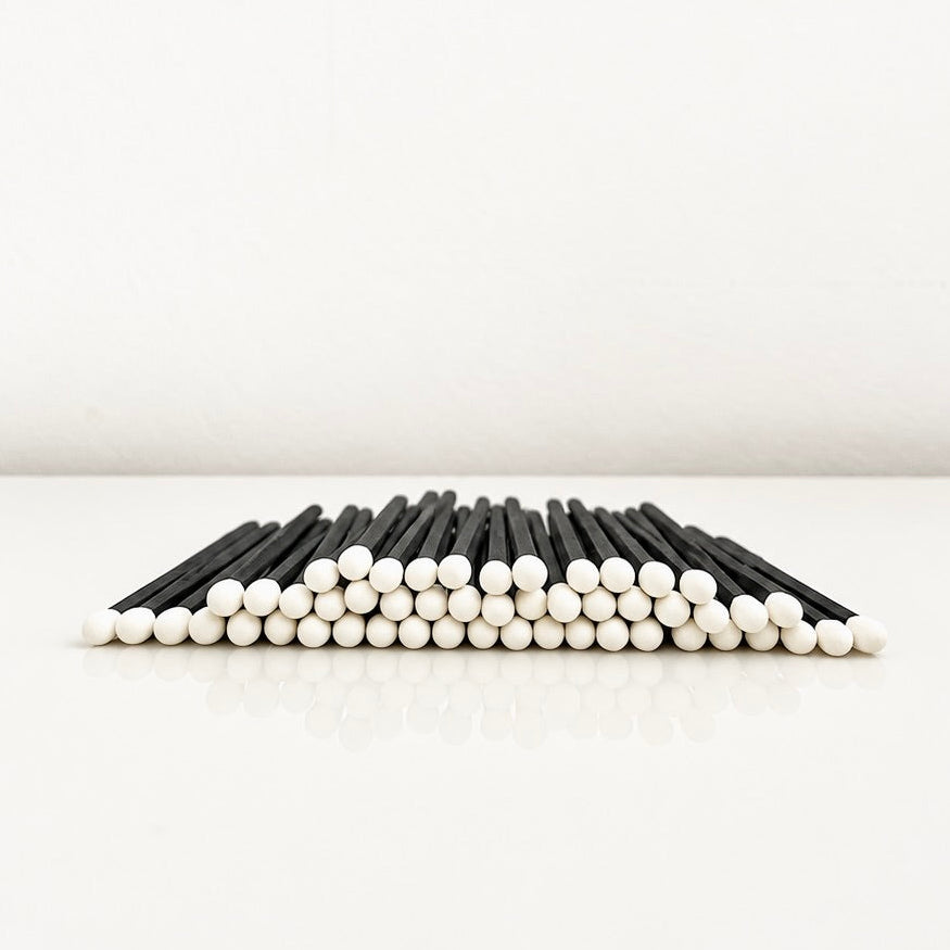 7.5 cm black and white safety matches on a white surface.