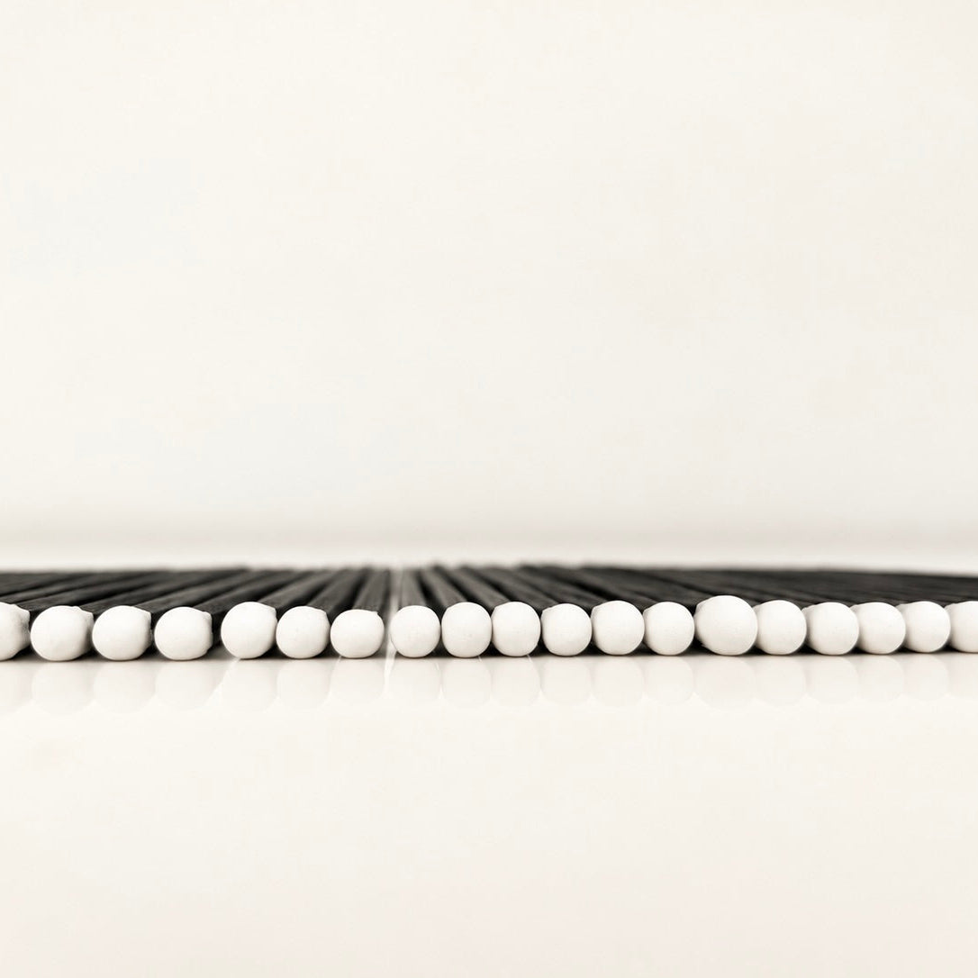 Line of 7.5 cm black and white safety matches on a white surface.