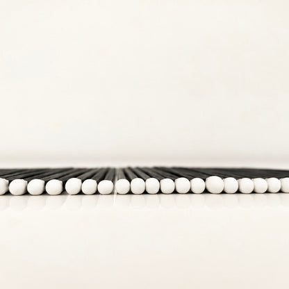 Line of 7.5 cm black and white safety matches on a white surface.
