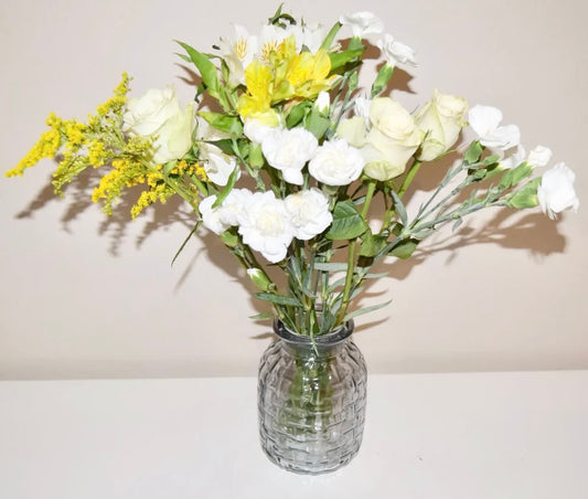 Blue ribbed glass vase with fresh flowers on a white surface.