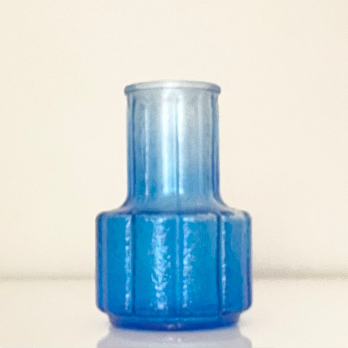 Blue glass vase (D) with textured surface on a white background.