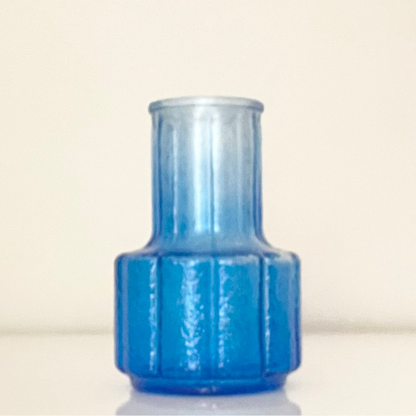 Blue glass vase (D) with textured surface on a white background.