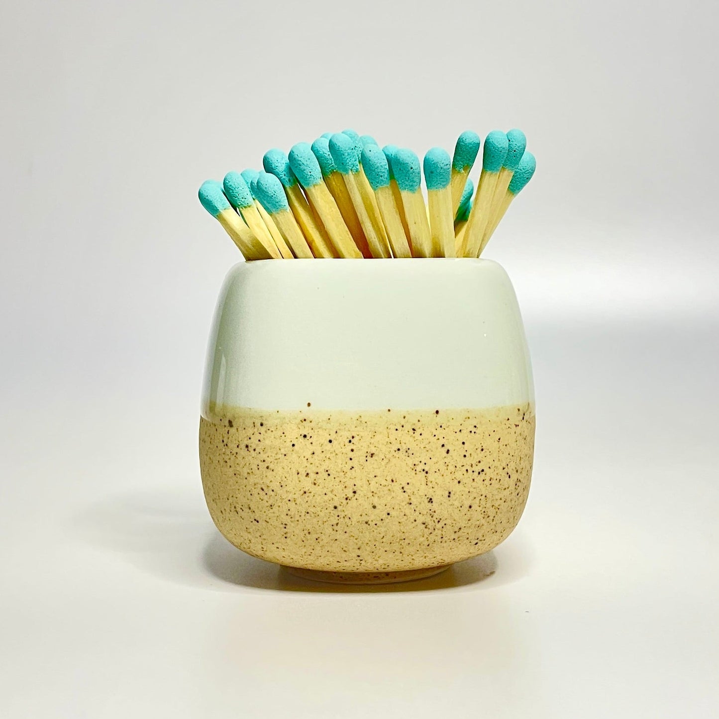 Blue ceramic match holder on a white surface.