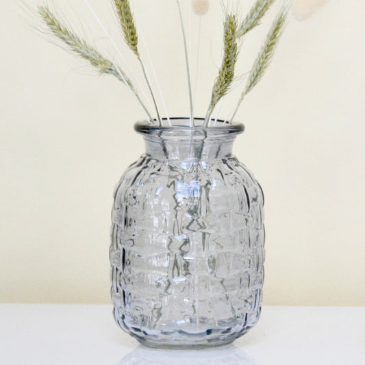 Blue ribbed glass vase on a white surface against a light yellow background.