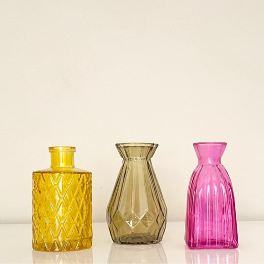 Artisanal colourful glass bottles on a white background.