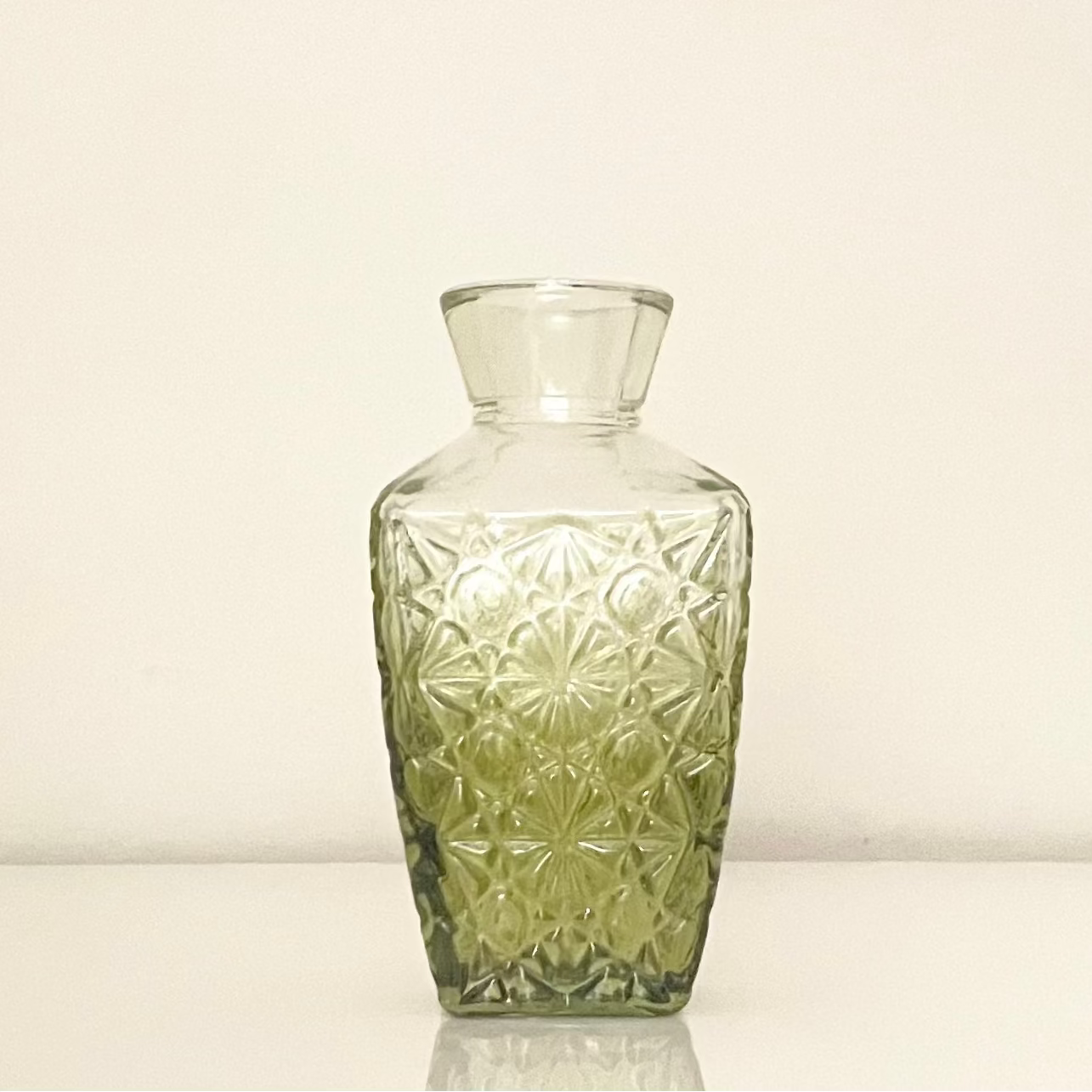 Green glass vase (C) with textured surface on a white background.