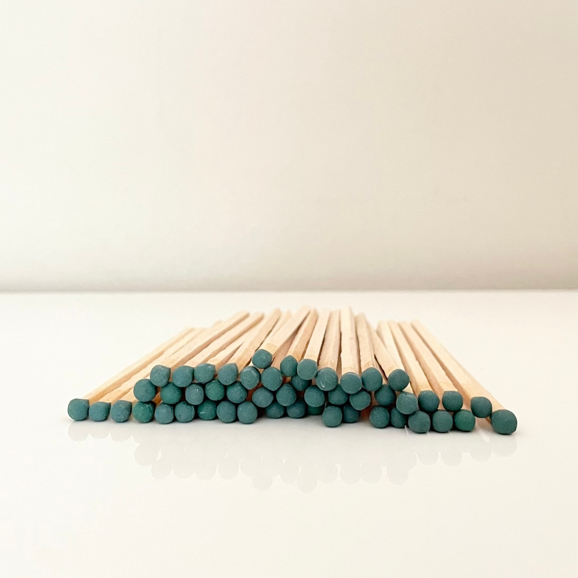 9.8 cm dark green matches on a white surface. 