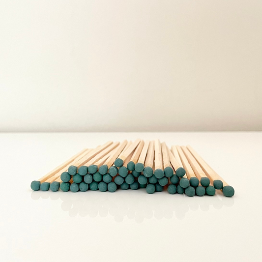 9.8 cm dark green matches on a white surface. 