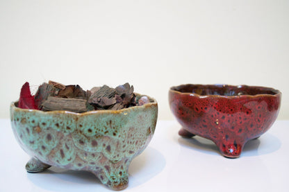 Two ceramic bowls, one green and the other red with speckled pattern, on a white background.
