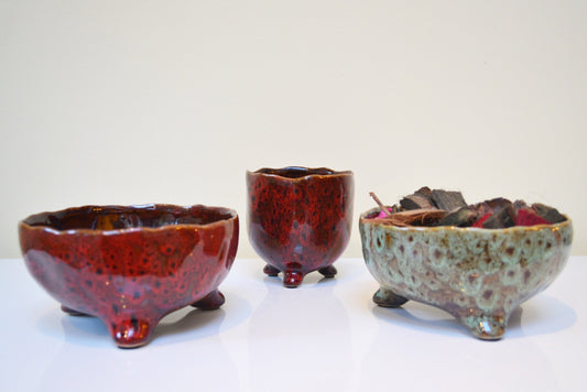 Glazed ceramic pot and bowls with unique  colours on a white background.