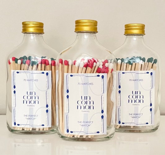 Gold lid glass bottles filled with 9.8 cm red, dark green and white matches on a white background.