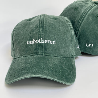 100% Green washed cotton cap with 'unbothered' white embroidery with side emblem 'un'. 