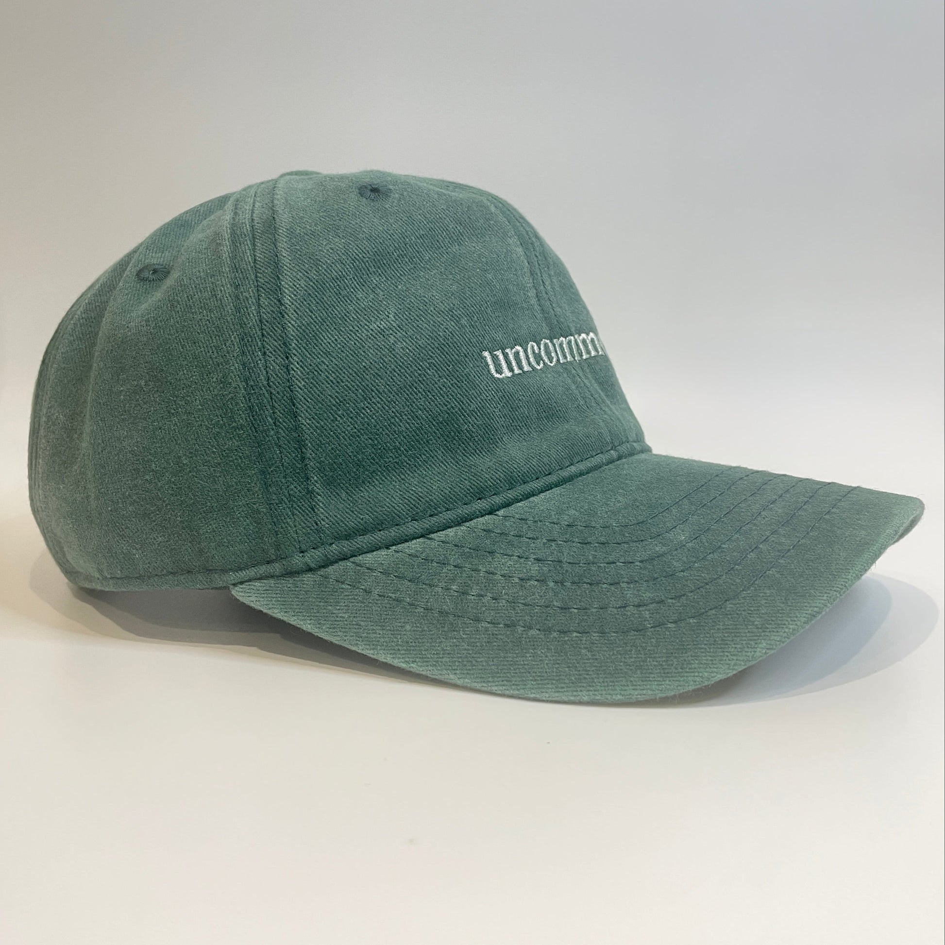 100% Green washed cotton cap with 'uncommon' white embroidery. 