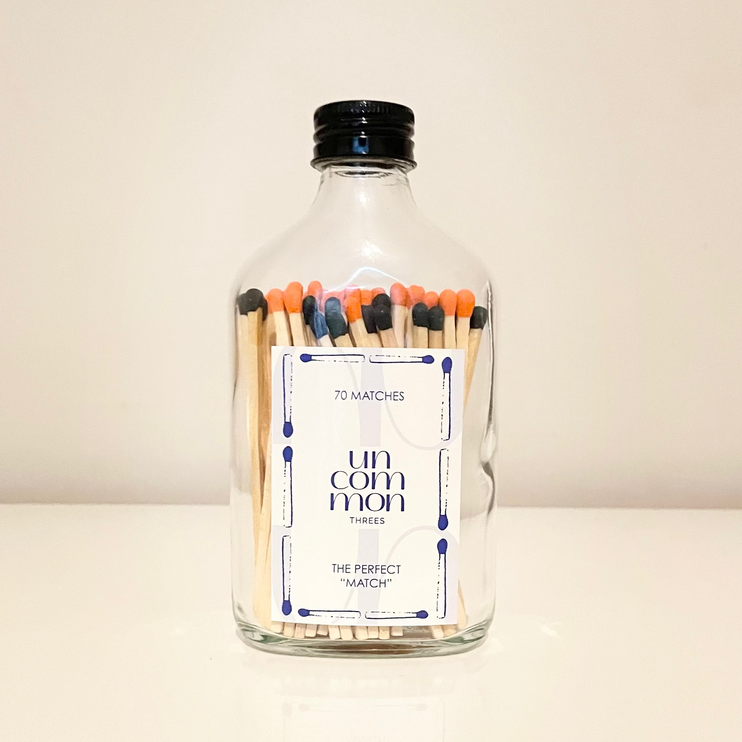 Black lid glass bottles filled with 9.8 cm black and orange and white matches on a white background.