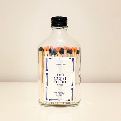 Black lid glass bottles filled with 9.8 cm black and orange and white matches on a white background.