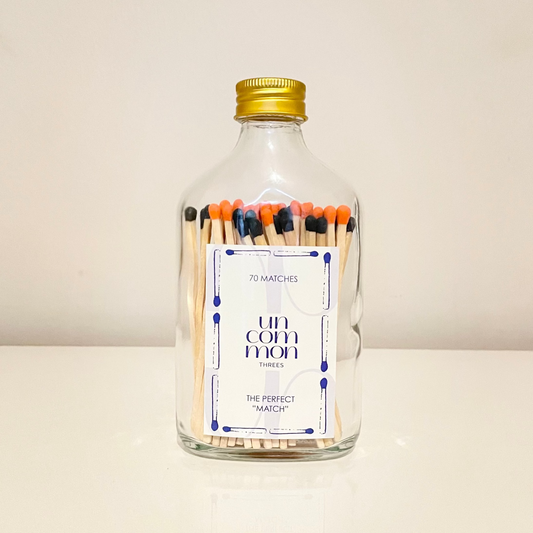 Gold lid glass bottles filled with 9.8 cm black and orange matches on a white background.