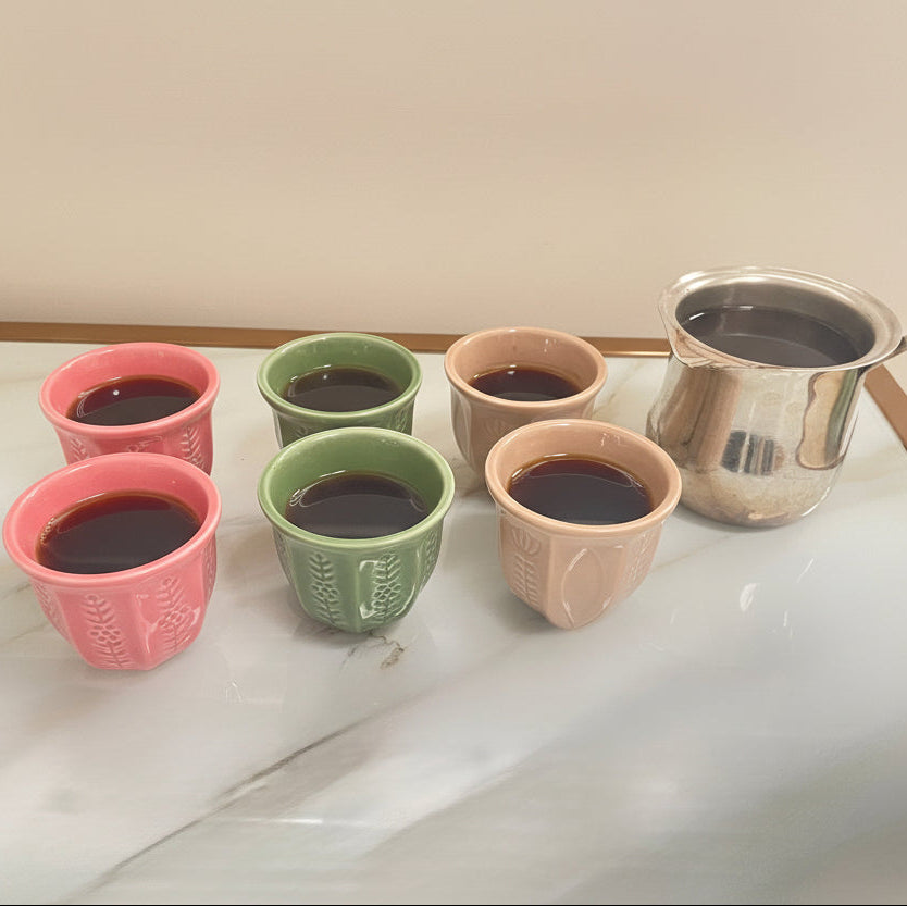 Ceramic coffee mugs in the colours beige, pink, and green.