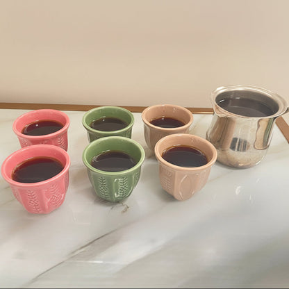 Ceramic coffee mugs in the colours beige, pink, and green.