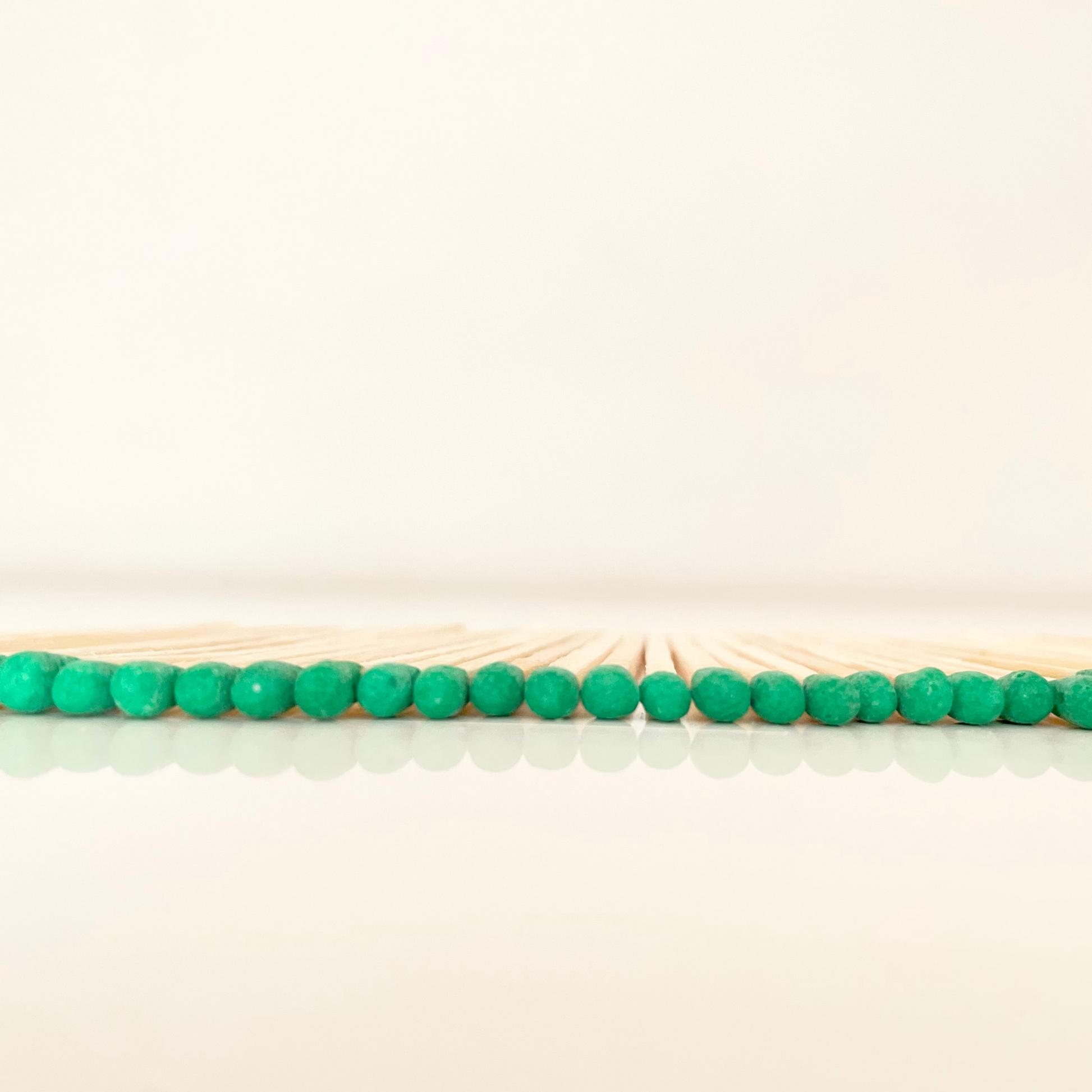 4.8 cm green matches on a white surface. 