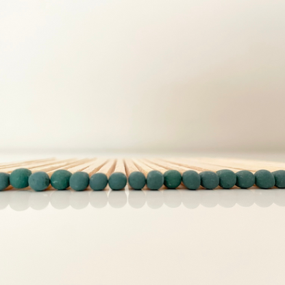 9.8 cm dark green matches on white surface.
