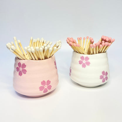 Pink and white ceramic flower safety match hodlers that can also be used as a coffee cup.