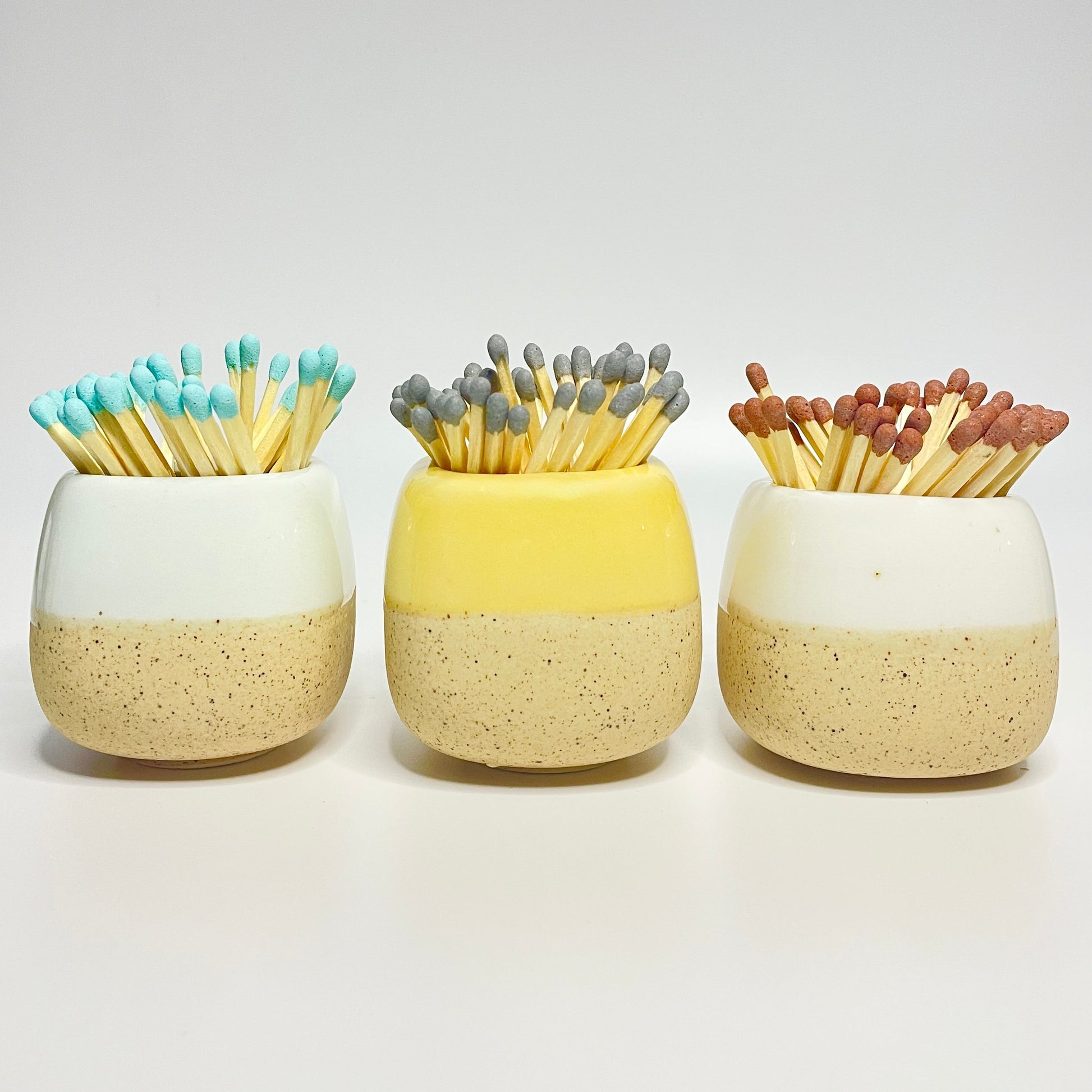 Pastel ceramic match holders on a white surface.