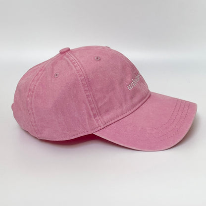 100% Pink washed cotton cap with 'unbothered' white embroidery with side emblem 'un'. 