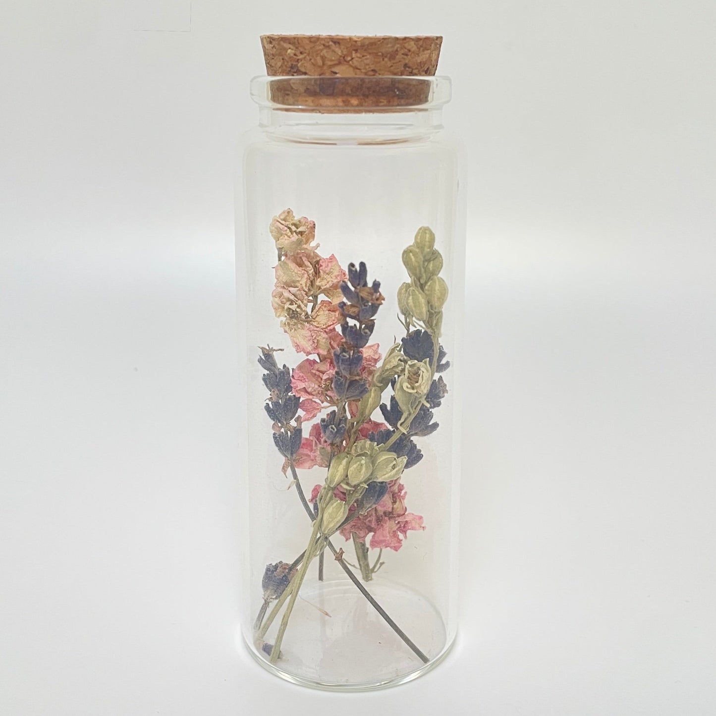 Test tube glass bottle filled with dried delphinium and lavender. 