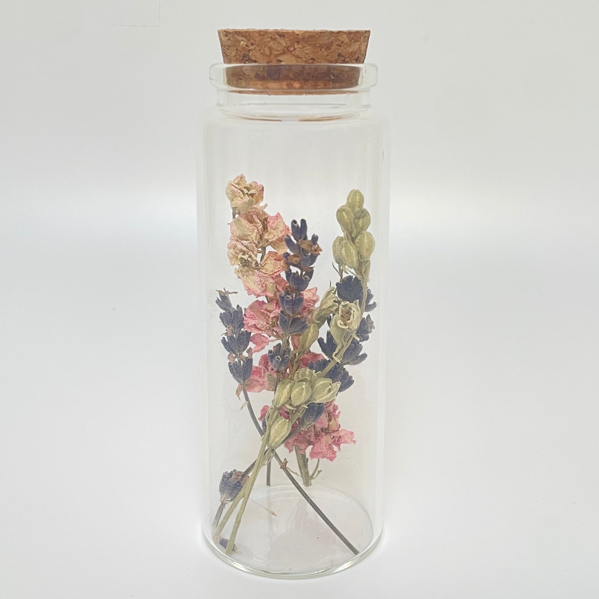 Test tube glass bottle filled with dried delphinium and lavender. 