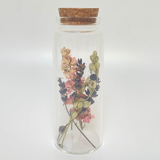 Test tube glass bottle filled with dried delphinium and lavender. 