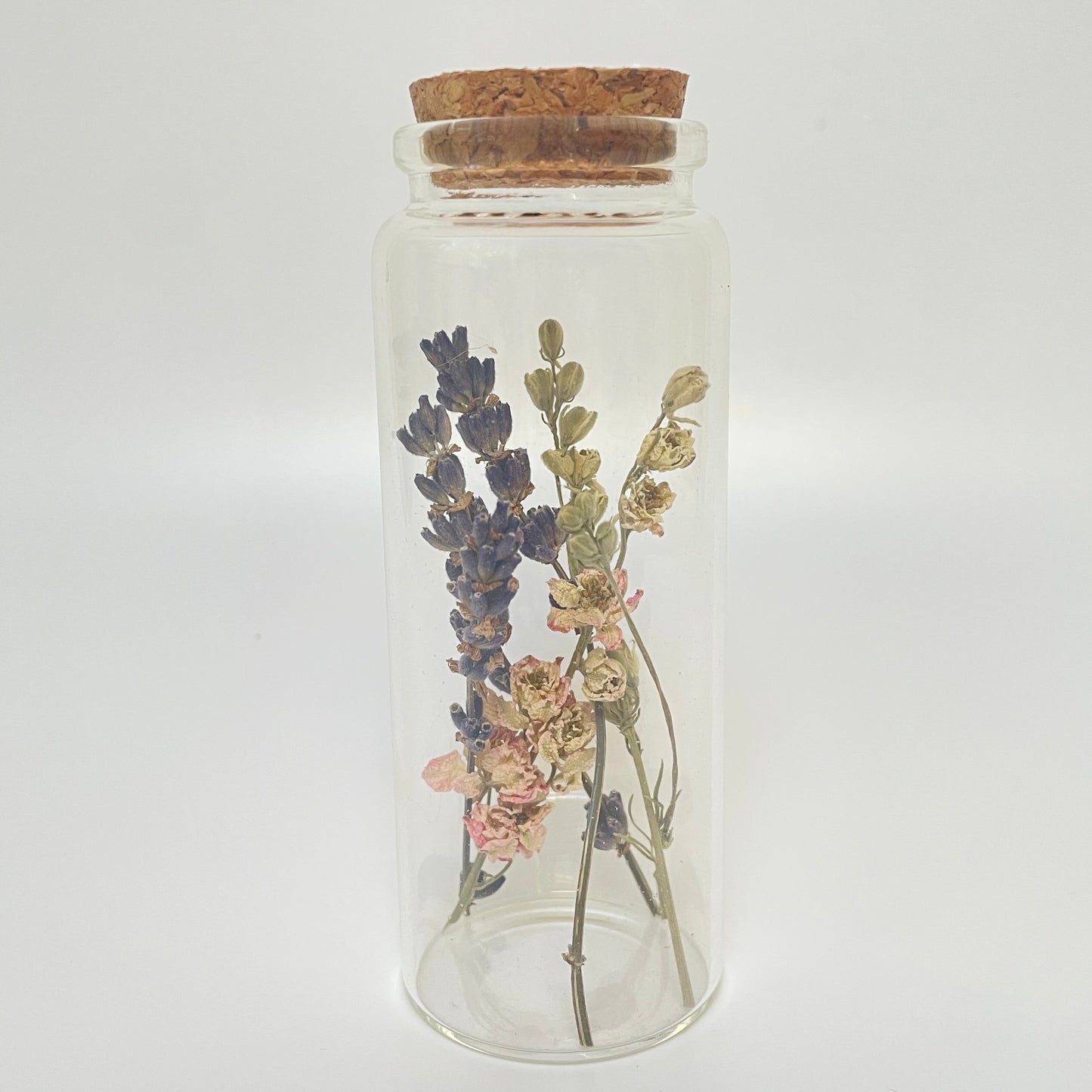 Test tube glass bottle filled with dried delphinium and lavender. 