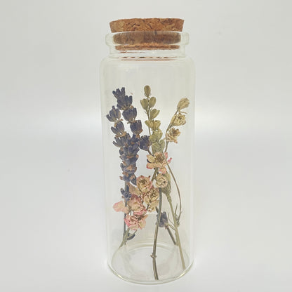 Test tube glass bottle filled with dried delphinium and lavender. 